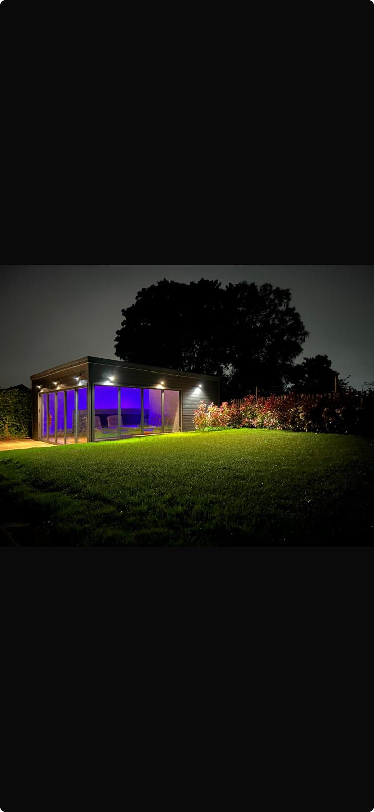 Garden room at night with purple LED interior lighting and exterior spotlights